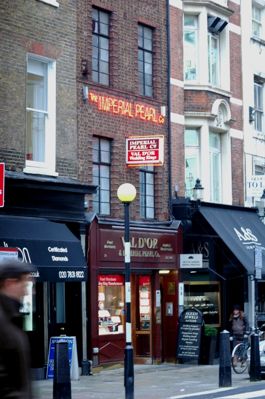 people walk near shops and restaurants on a city street