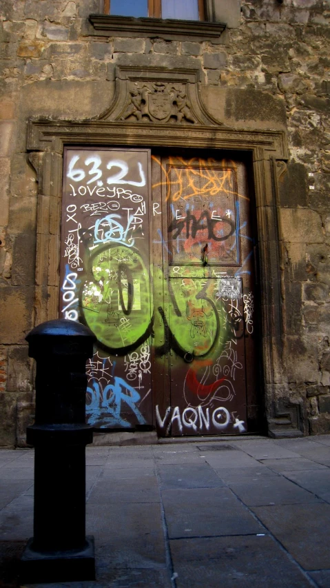 a graffitied door with a pedestal on a brick street