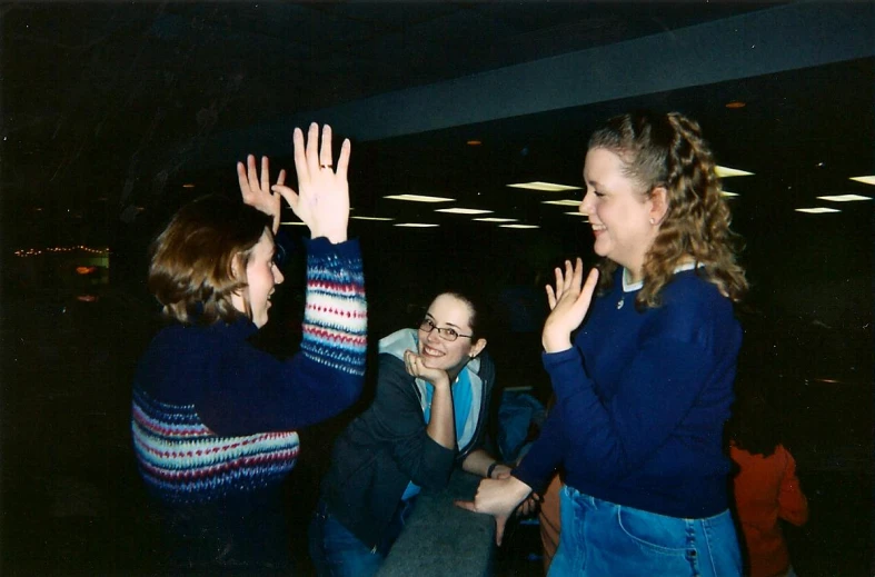 some people standing around a building and two are waving their hands