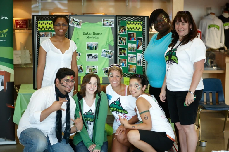 several girls and a boy in white shirts, black pants, and black ties pose for a group po