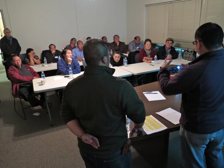 people in a conference room with many talking and others sitting at long tables