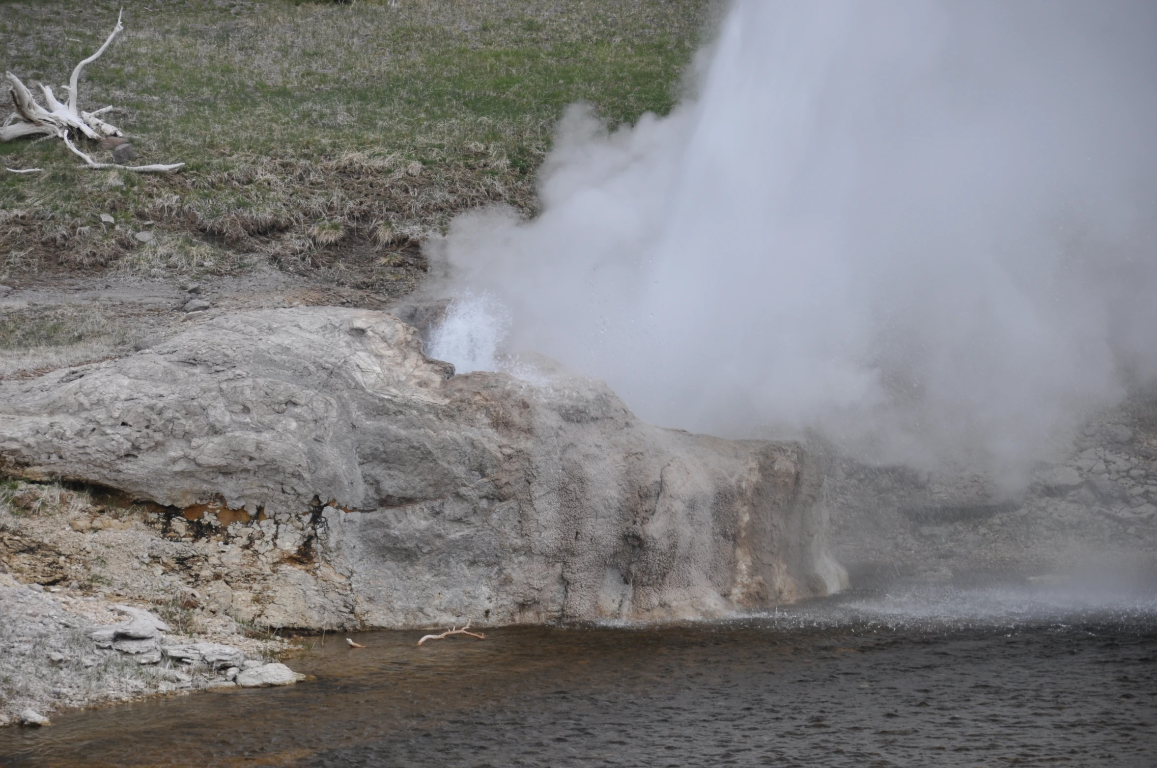 a group of geysers near a small body of water