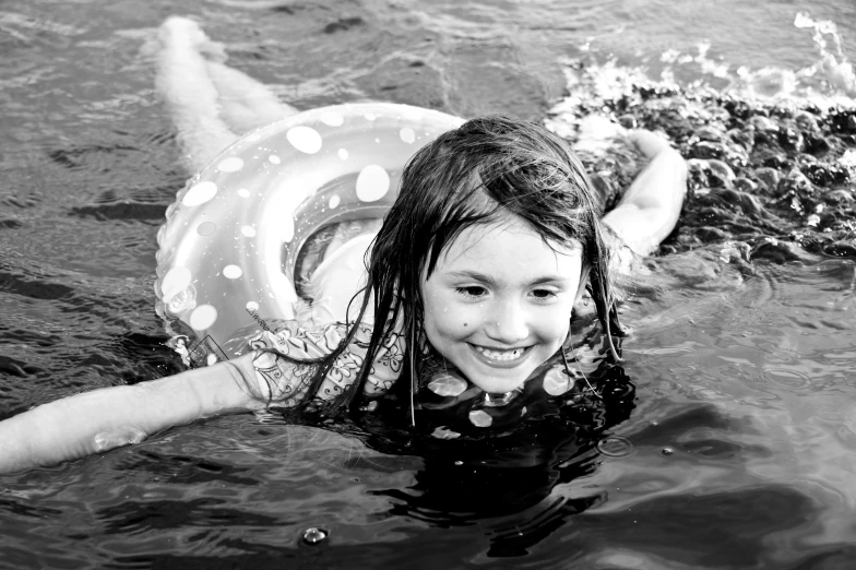 a girl in the water with a giant inner tube on her back