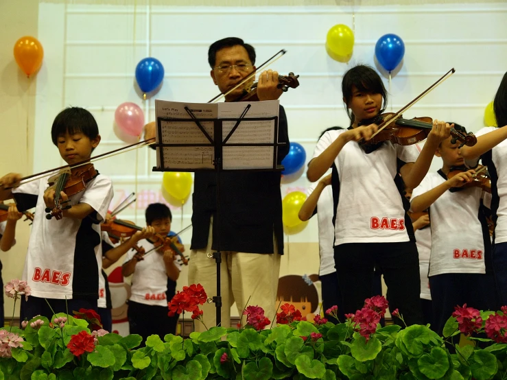 children singing and playing violin with conductor