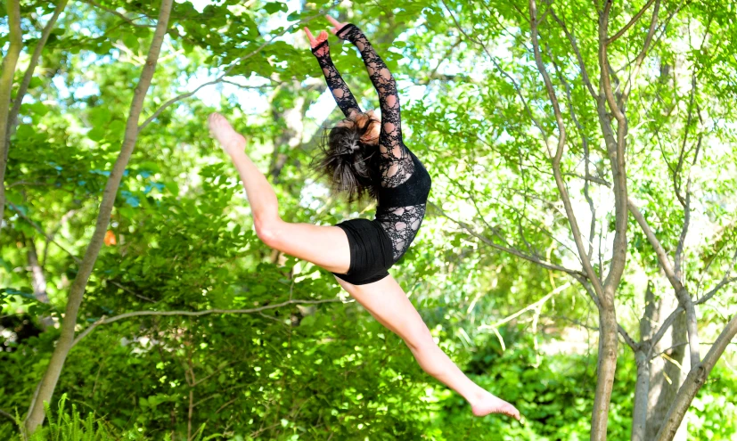 a woman suspended by an upside down tree limb