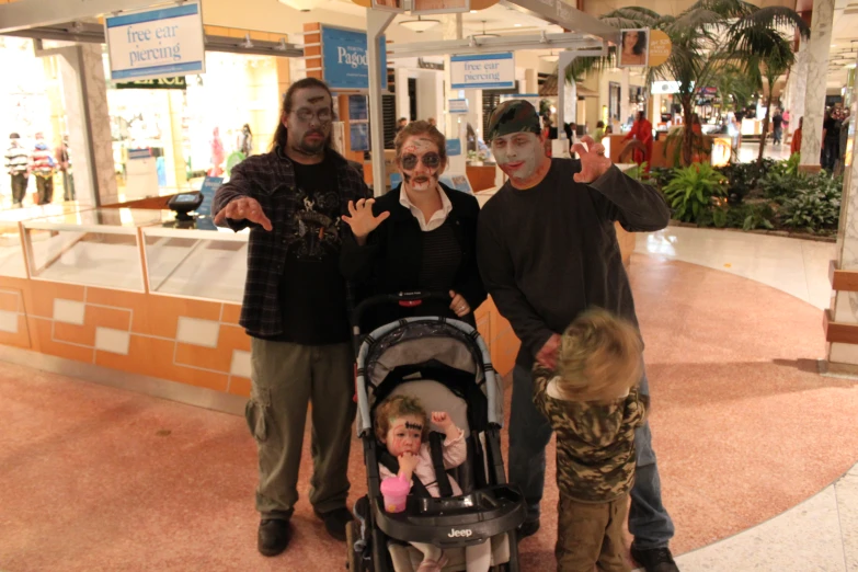 three people are standing in the mall holding their baby