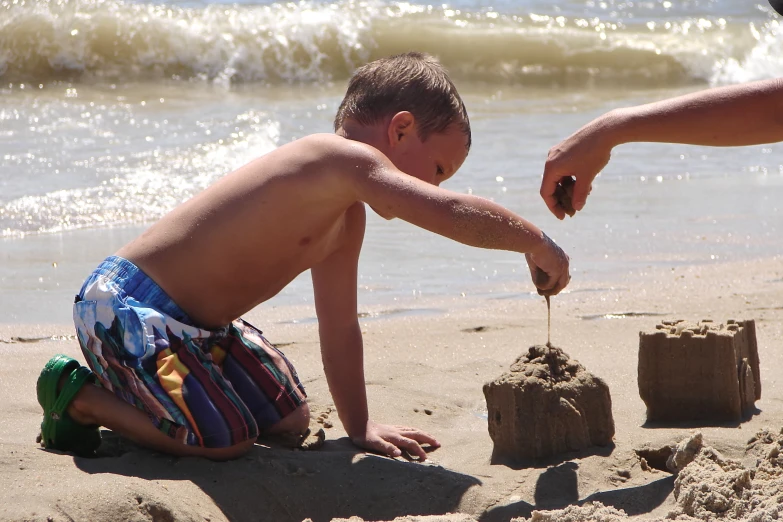 a boy building a castle out of the sand at the beach