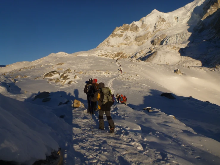 two people hiking up a snowy hill, looking at mountains