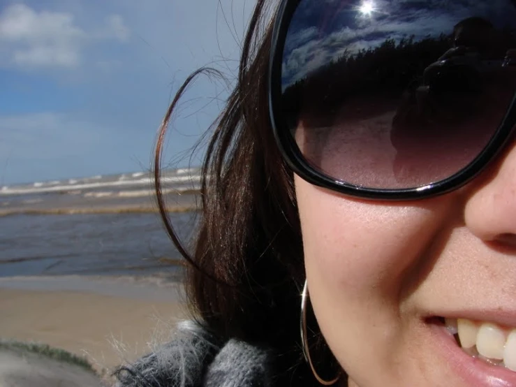 a woman wearing sunglasses on the shore of the beach