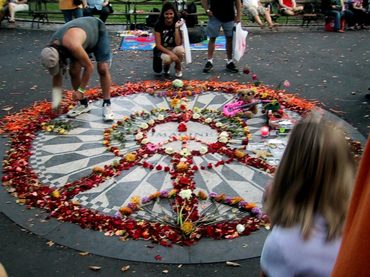 a crowd gathers in a park while the ground has flowers around it