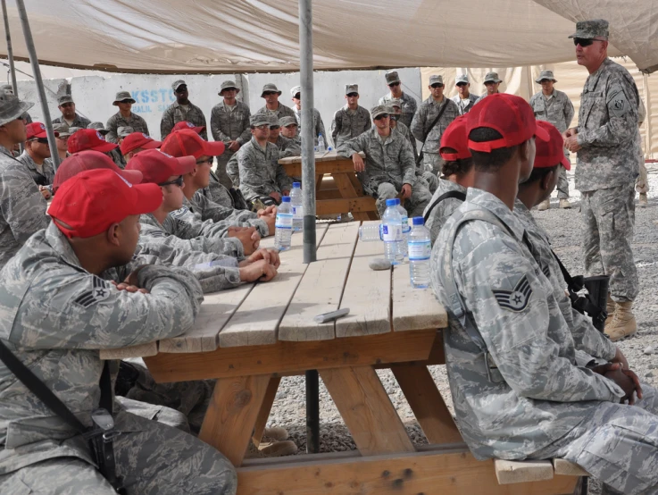 two soldiers in uniform sitting at a table next to other soldiers