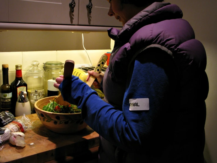 a person is cooking in the kitchen, she is wearing a purple coat