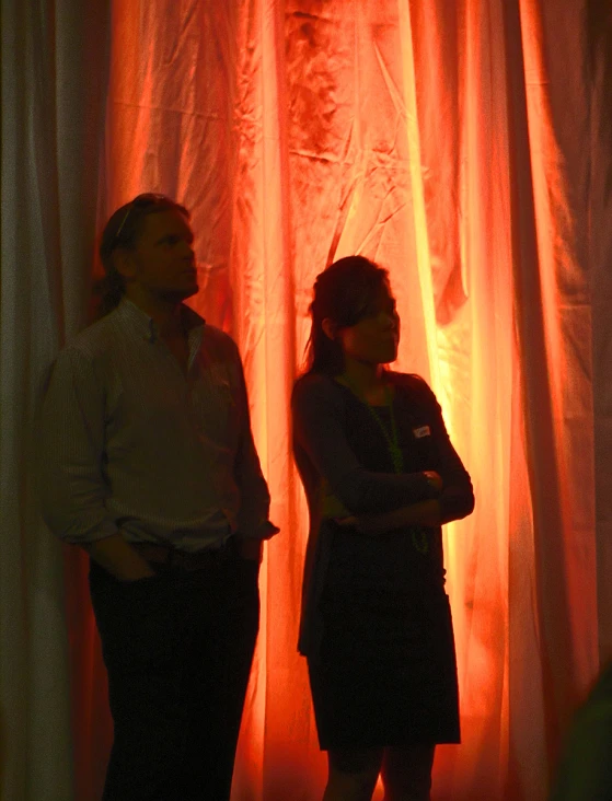 a couple of people standing in front of a curtain