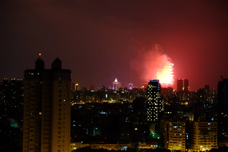 fireworks are lit up in the sky behind tall buildings