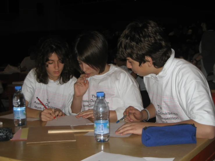 s and boys wearing white shirts sitting at a desk