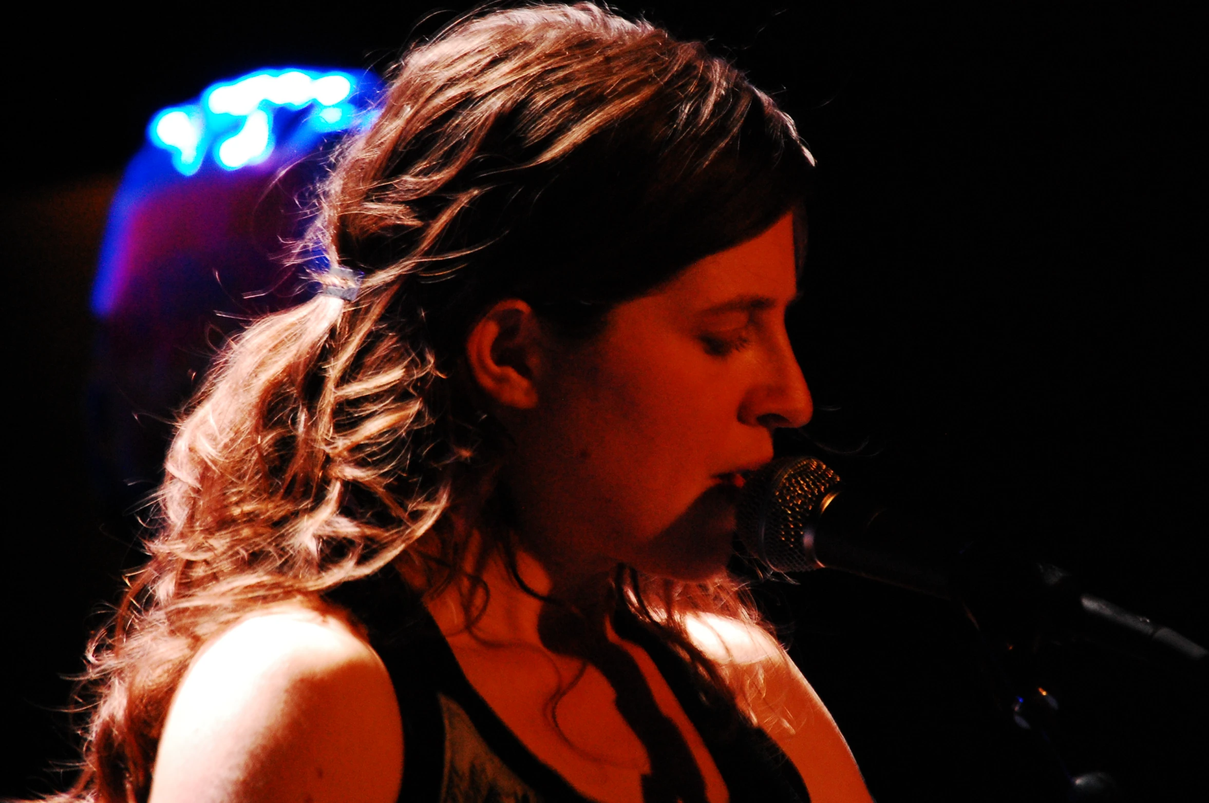 a female in black shirt and tank top singing into a microphone