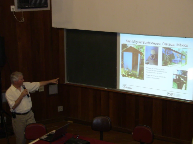 a man standing in front of a projector screen giving a presentation