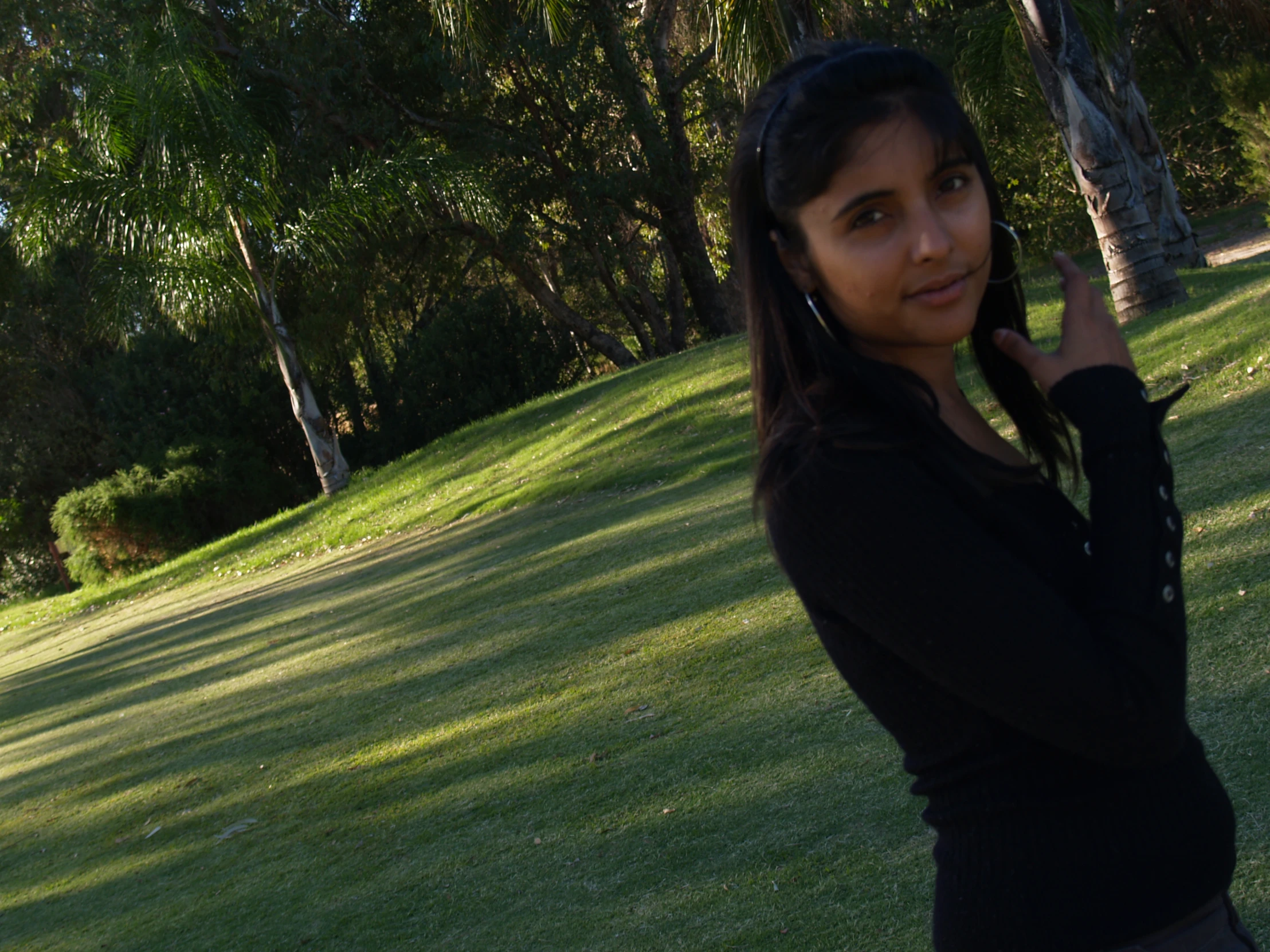 a woman standing in the grass on her cell phone