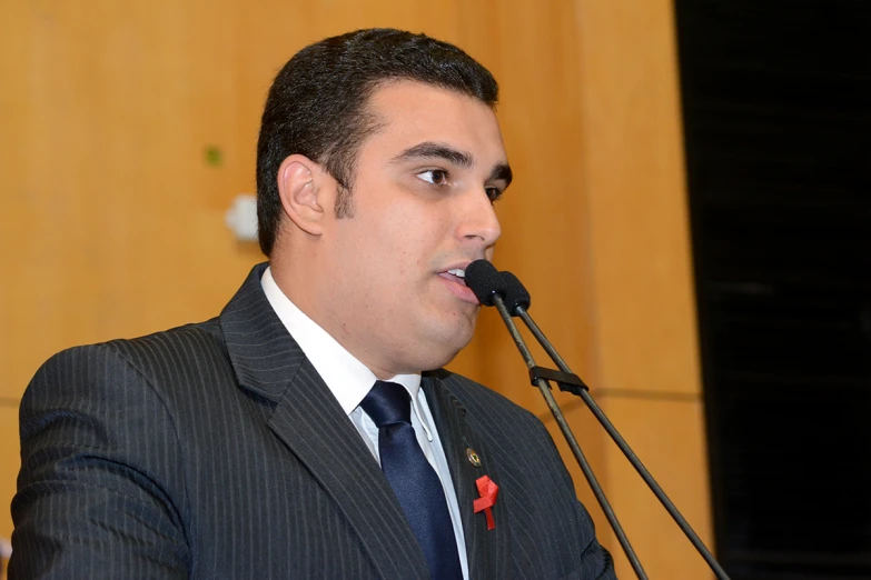 a man in suit and tie standing up with microphone