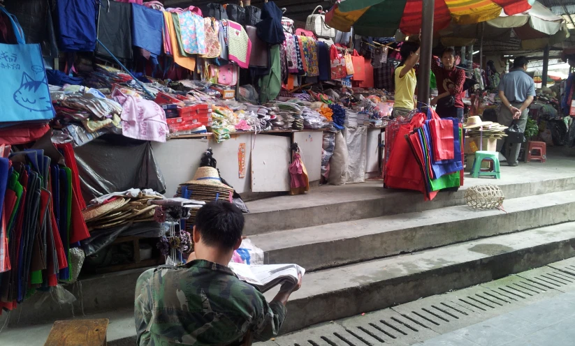 a man sits under an umbrella at a market