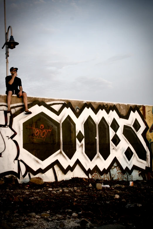 a man sitting on top of graffiti covered wall