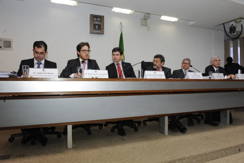 there are many men in suits that are sitting at the table