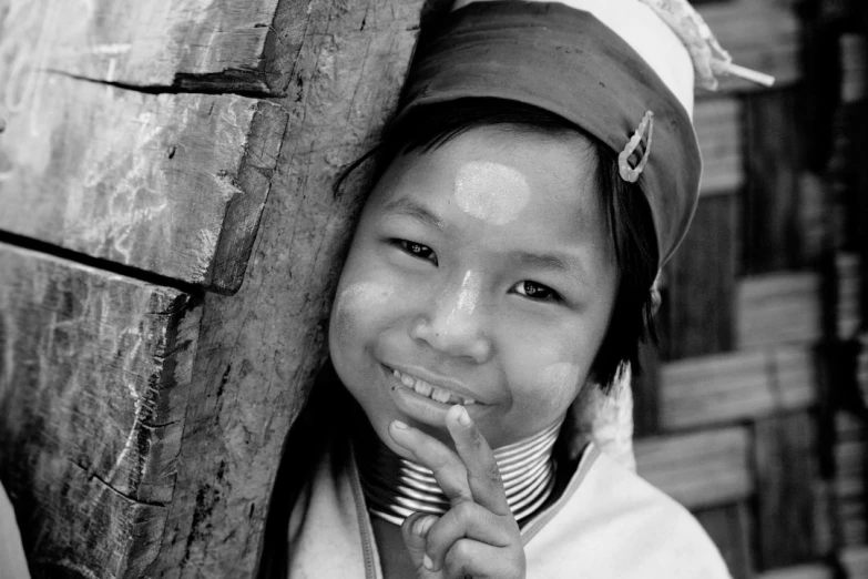 an asian girl leaning against a wooden post