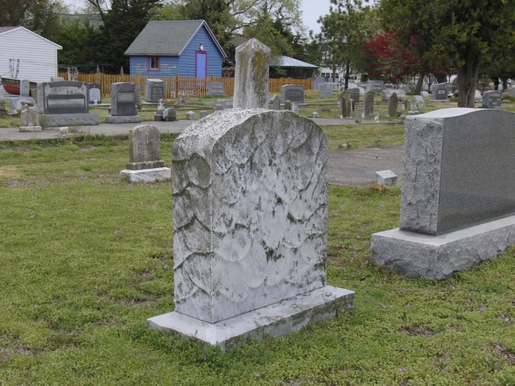 a white tombstone surrounded by grass on top of a cemetery