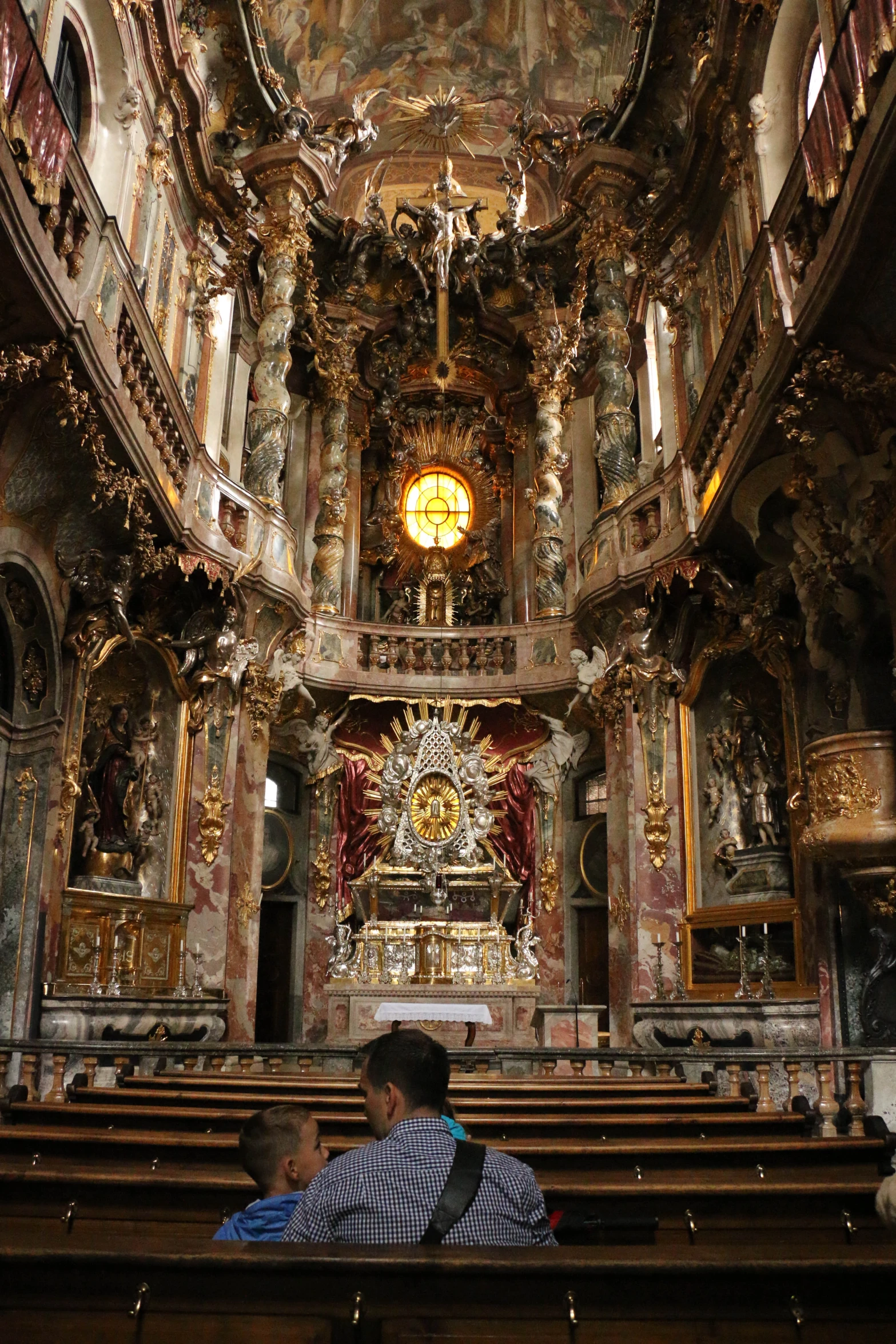 several people sitting in a large church, one in front of the other