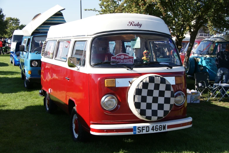 several vans with people standing in the grass