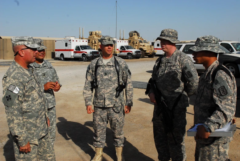 several military men standing around a vehicle