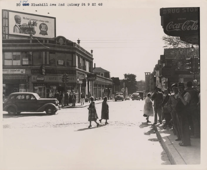 people stand on the side walk near an old town