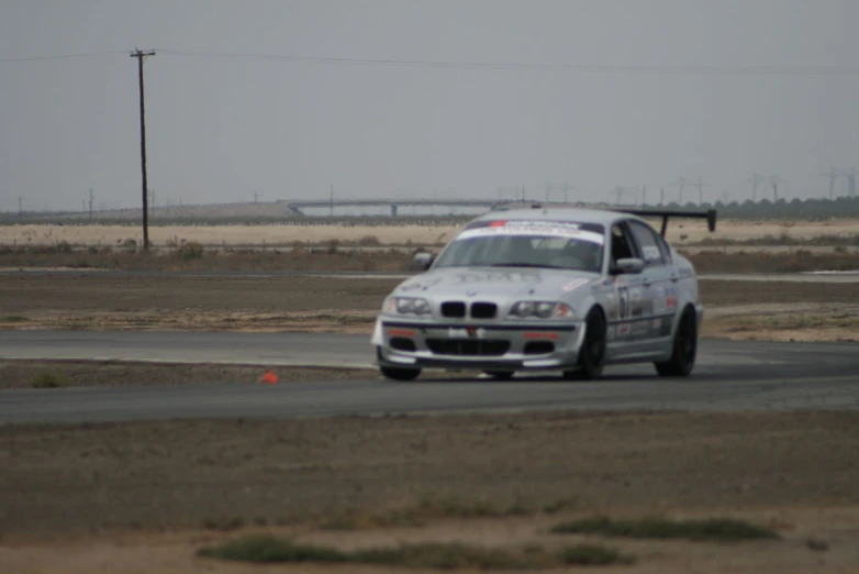 a white bmw that is driving on the road