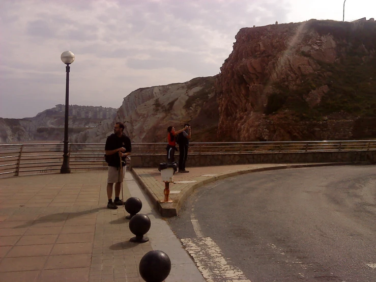 two people talking while standing on a road side