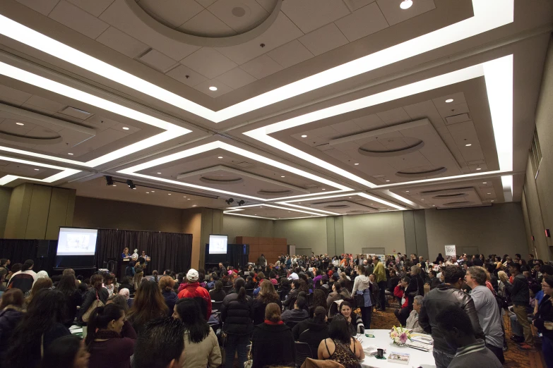 people in conference hall listening to speakers and presentations