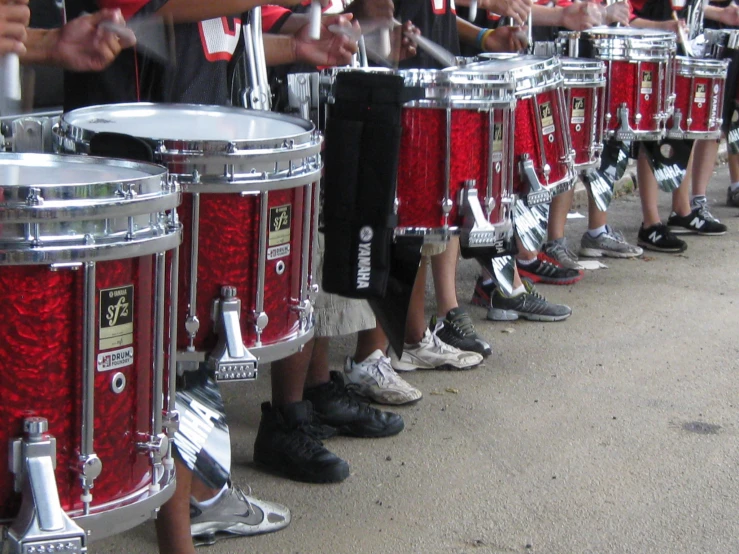 a line up of boys in sports gear standing next to drum sets