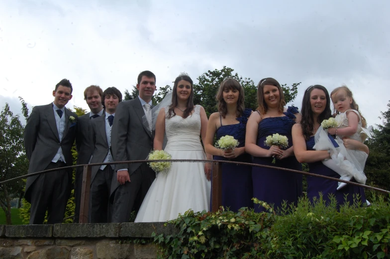 a wedding party poses together on a bridge