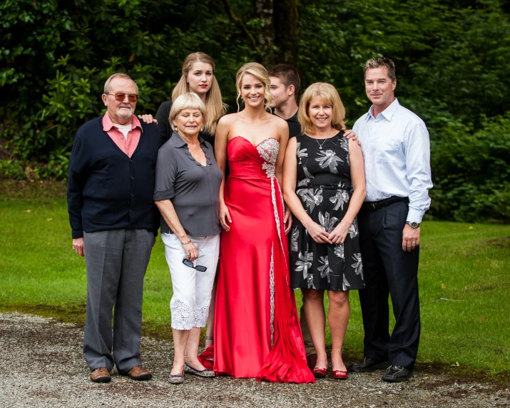 family portrait in front of green trees in a park