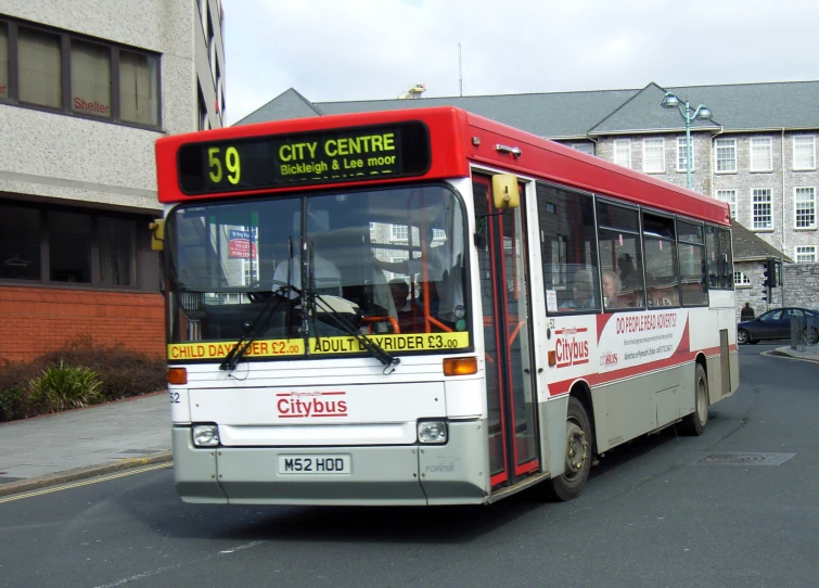 there is a red, white and black city bus on the street