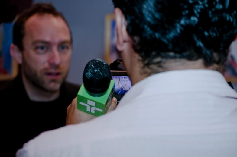 two people in a room one with a microphone and the other holding a video camera