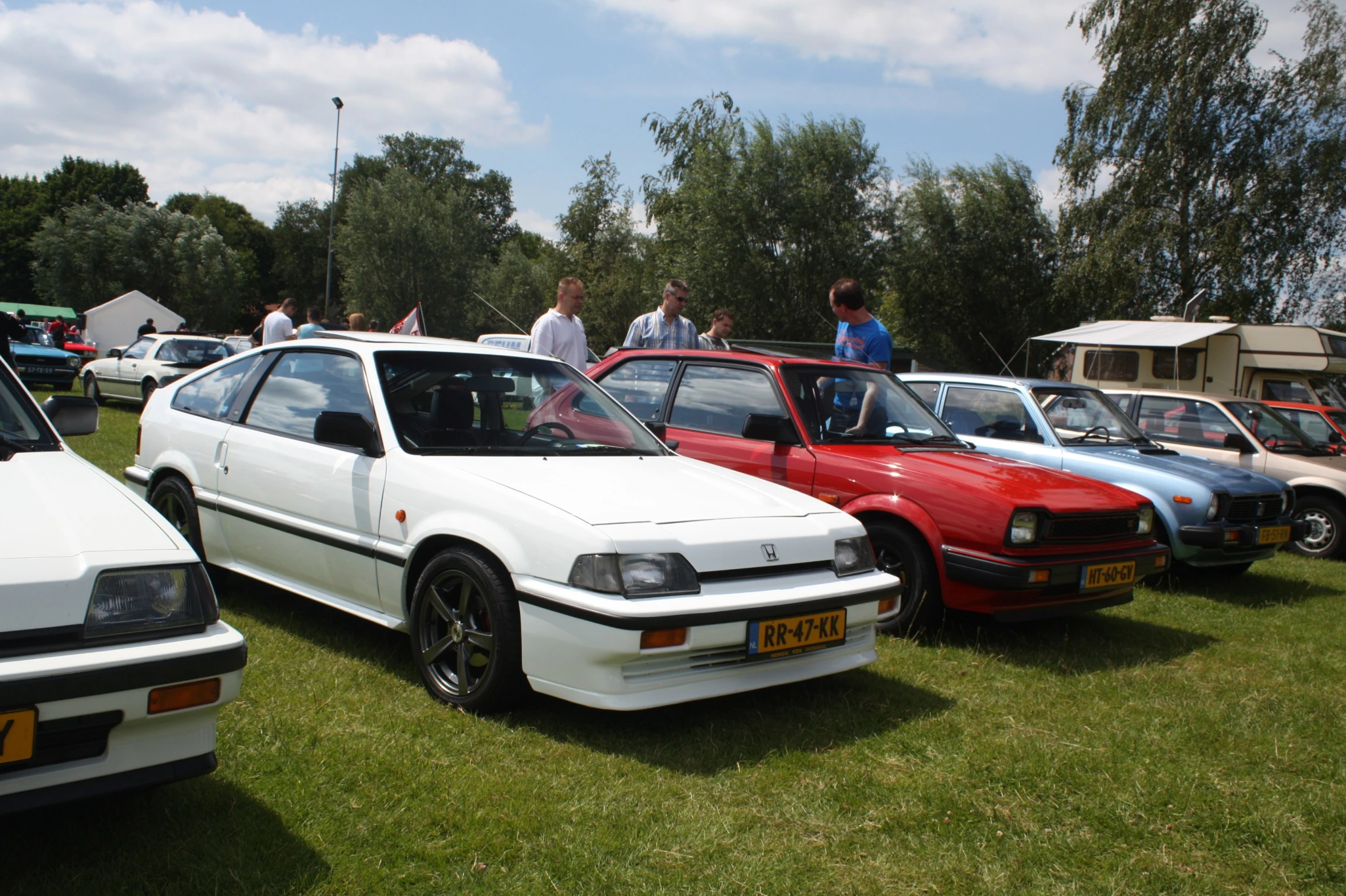 a group of cars parked on top of a grass covered field