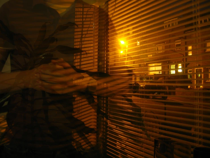 a man standing by a window looking out at the city at night