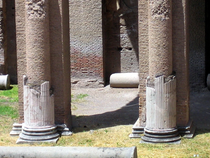 three columns standing in an enclosed area with grass