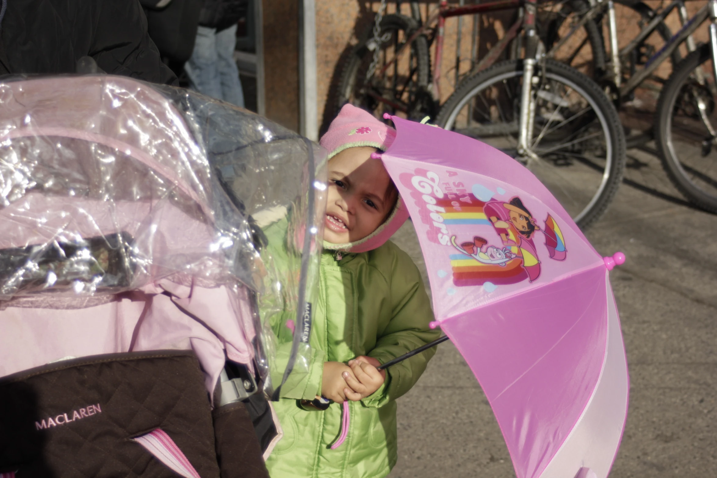 a little girl is holding a pink umbrella in a park