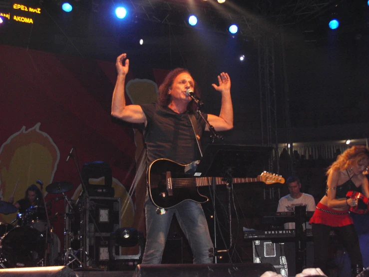 a person on stage with a guitar and people behind him