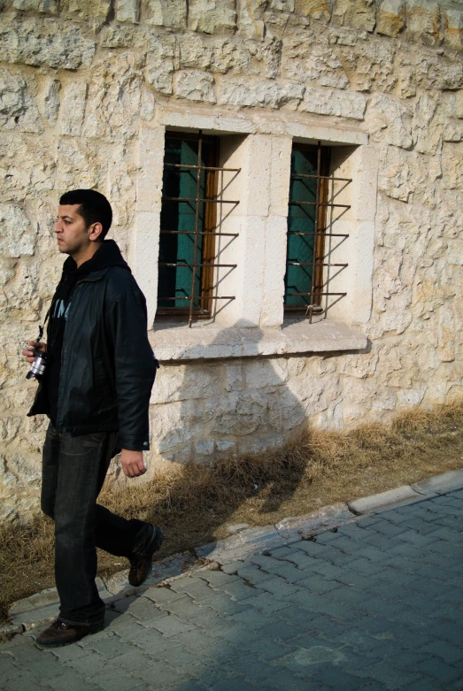 a man walking down a street in front of a tall brick building