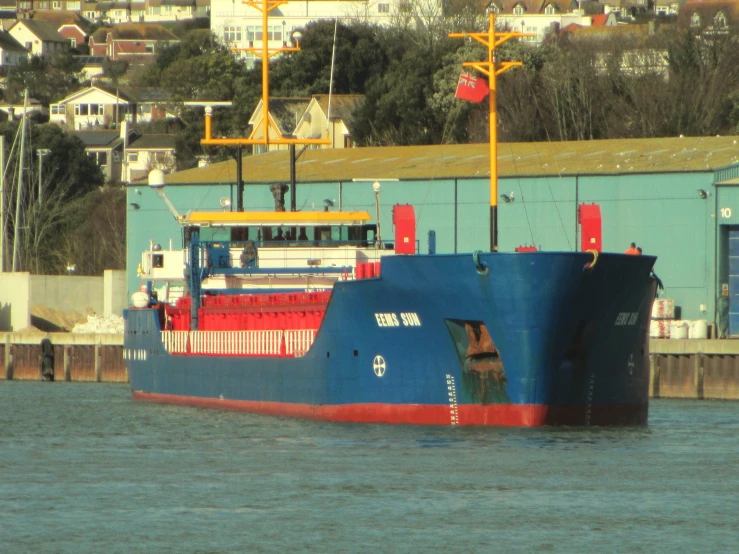 large blue and red ship moving down water