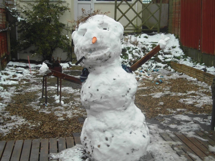 there is a snowman outside next to a wooden deck