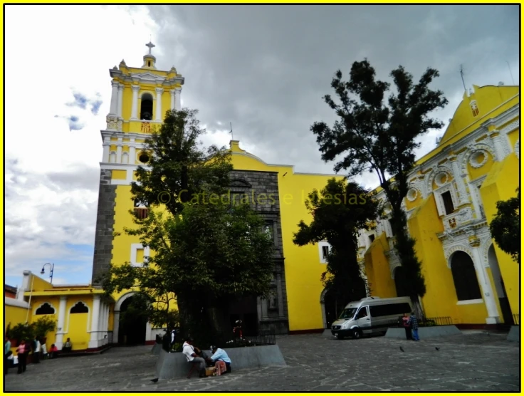 a yellow church with people seated on the steps