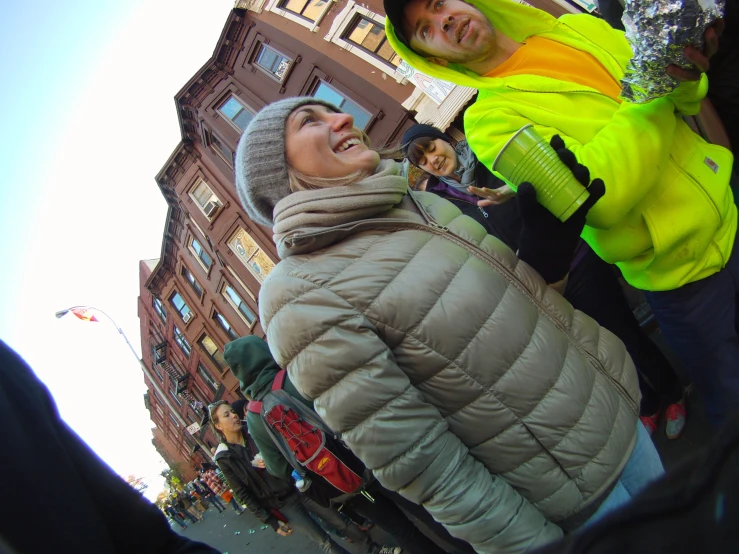 a man looking up in a jacket while another person wearing a snowsuit watches